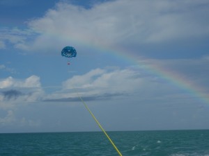 Tourists parasailing on a beautiful day with a rainbow in the background