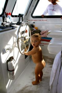 Naked baby driving a boat