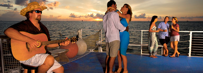Couple dancing on a Fury boat at Commotion on the Ocean event with a beautiful sunset in the background