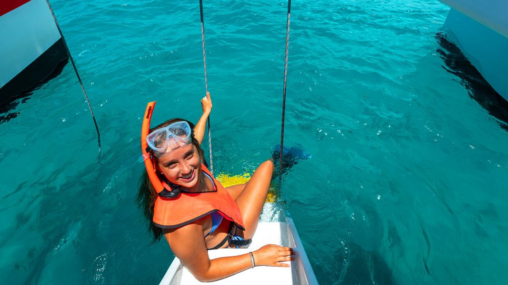 girl sitting on the stairway to the sea wearing snorkel gear on the reef express catamaran