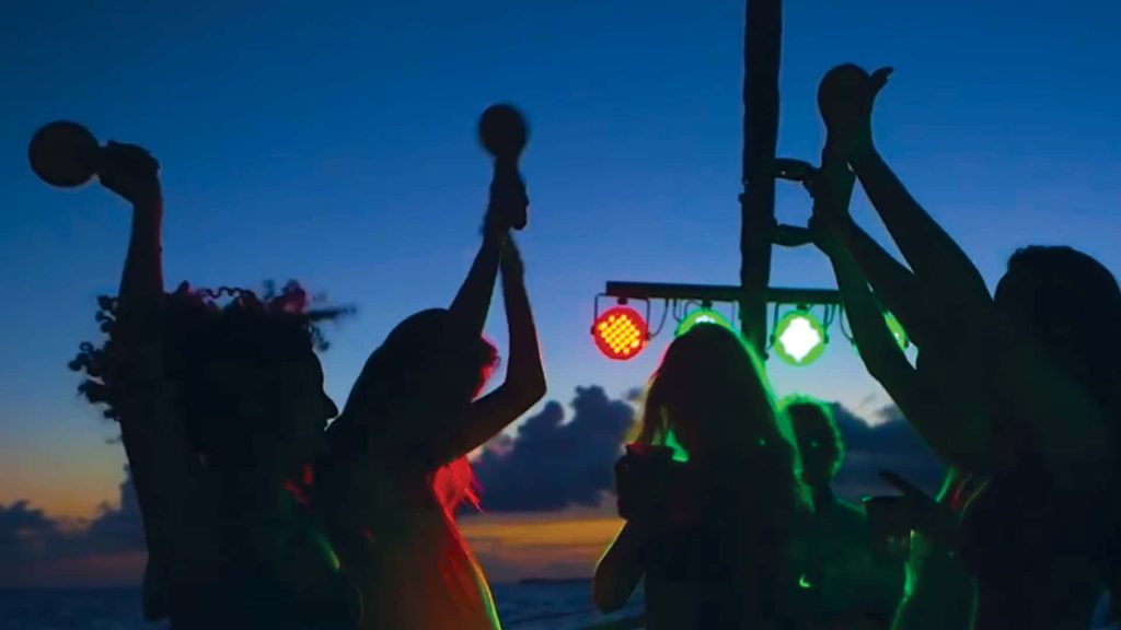 Guests dancing at night aboard Fury's Commotion on the Ocean sunset cruise with strobe lights and the ocean behind them.