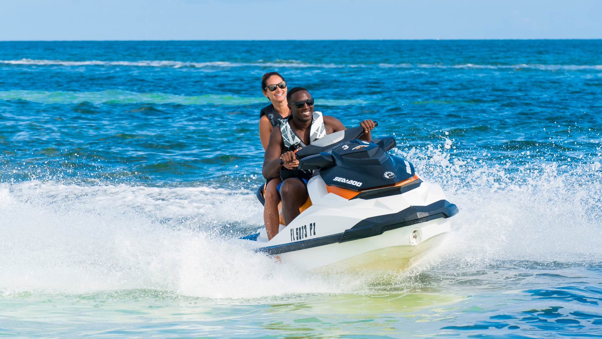 Man and woman riding a jet ski in choppy ocean waters