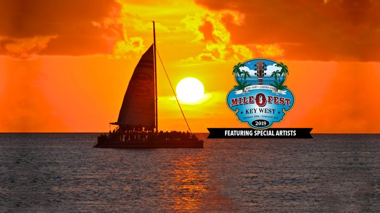 Key West sunset on the ocean with a Fury Catamaran carrying many guests and over the picture is the Mile 0 Festival logo. Logo is made up of the top of a guitar, palm trees and the words 'RED DIRT AMERICANA MILE O FEST KEY WEST January 29th to February 2nd 2019 Featuring Special Guests'.