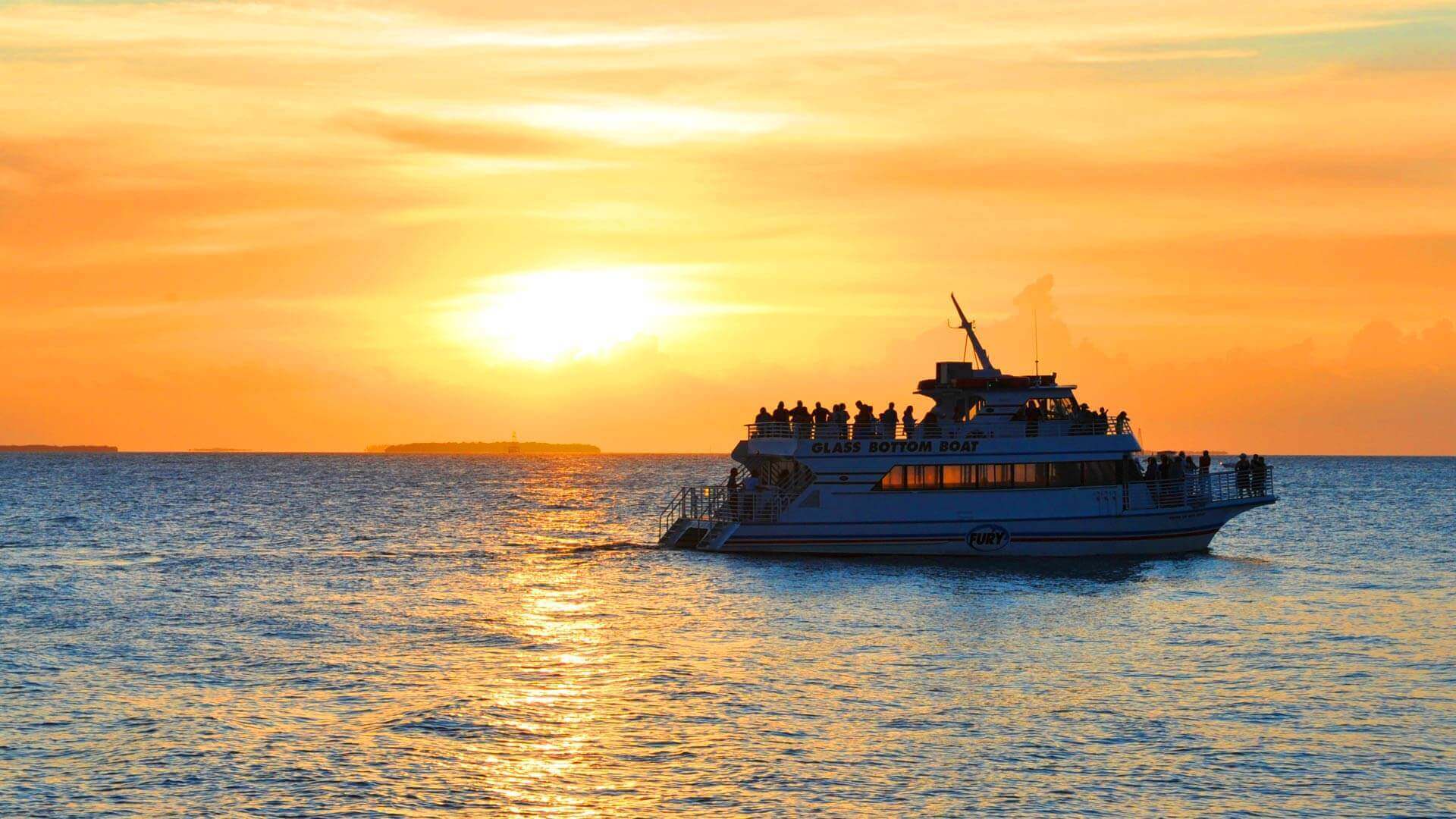 Tourists aboard Fury's glass bottom boat with sunset in background