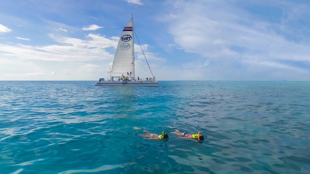 people reef snorkeling in key west with catamaran in background